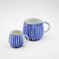 Two blue and white striped ceramic mugs on a white background