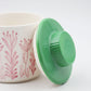 Container with pink floral design and green lid on a white background