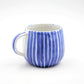 Ceramic mug with blue and white striped design on a white background