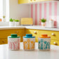 Three colorful canisters with floral patterns on a kitchen counter.