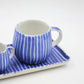 Two blue and white striped ceramic mugs on a matching tray with a white background