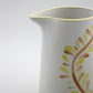 Ceramic pitcher with leaf design on a white background