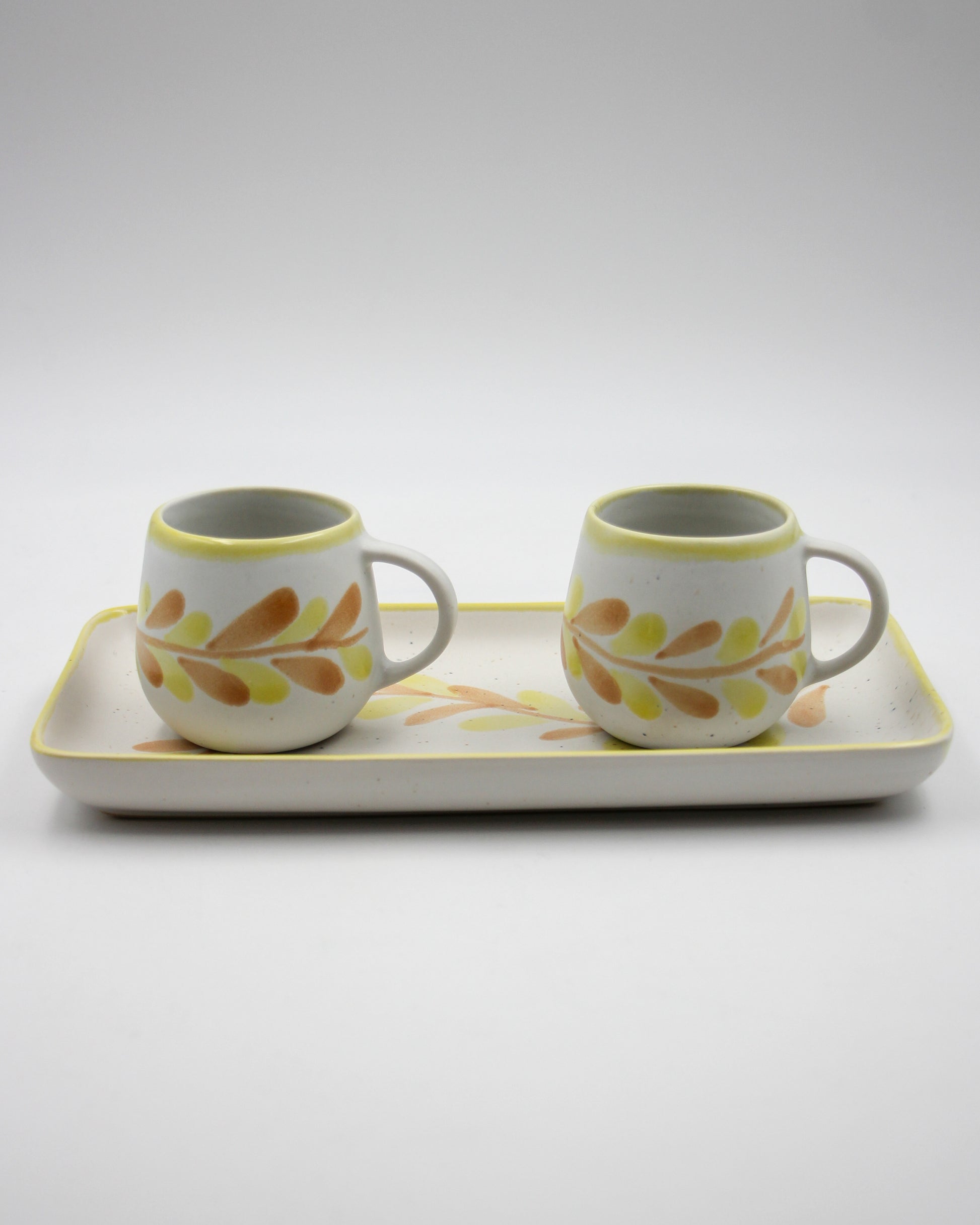 Two ceramic cups with a tray on a light gray background