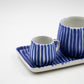 Two blue and white striped ceramic mugs on a matching tray with a white background