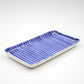 Rectangular ceramic tray with blue striped pattern on a white background