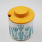 Container with a yellow lid and floral design on a white background