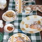 Breakfast table setting with croissants, coffee, and a checkered tablecloth.