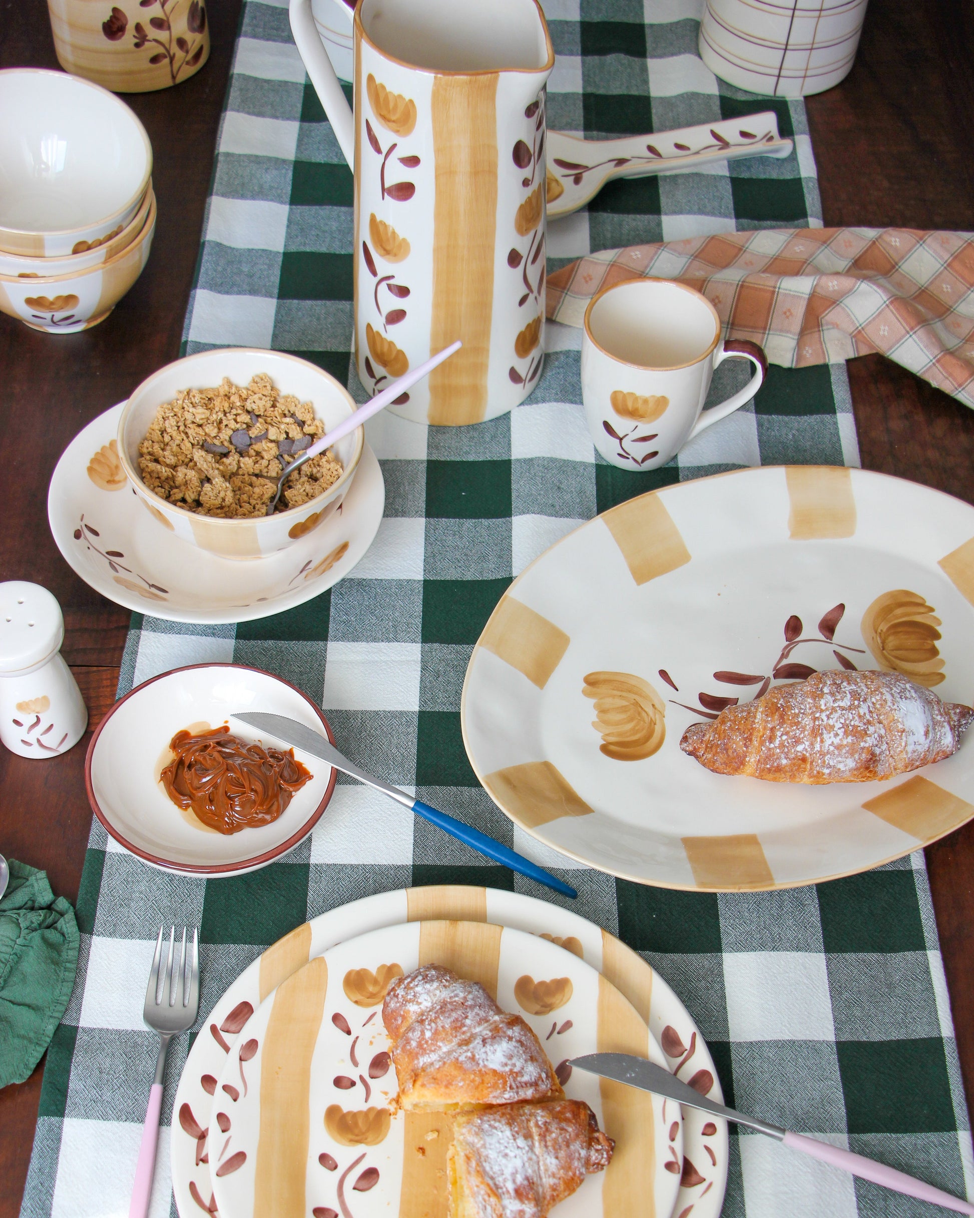 Breakfast table setting with croissants, coffee, and a checkered tablecloth.