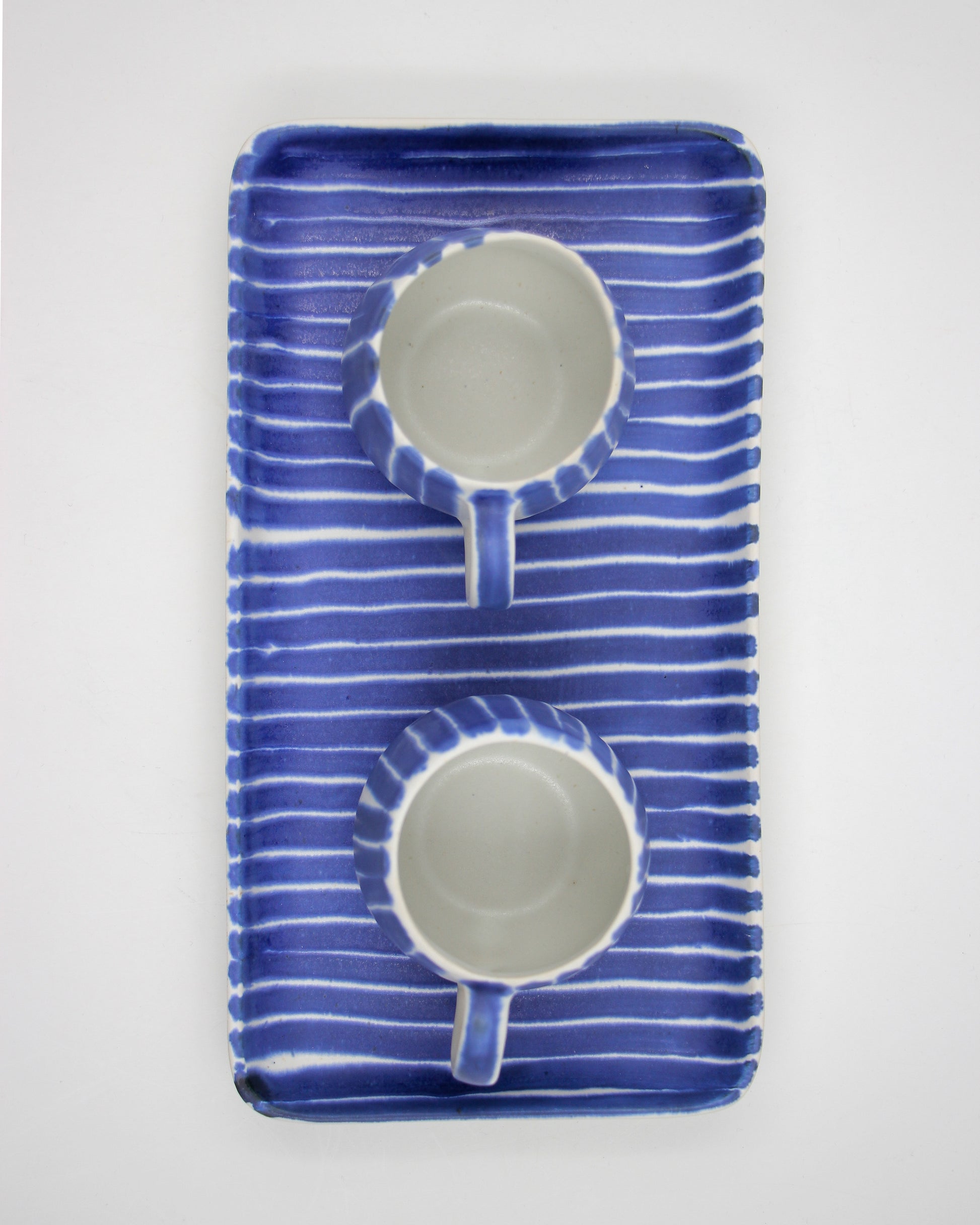 Blue striped ceramic cups and tray on a white background