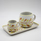 Two ceramic cups with a decorative pattern on a matching tray against a light gray background