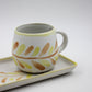 Ceramic mug with leaf pattern on a matching tray against a white background