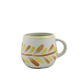 Ceramic mug with leaf pattern on a white background
