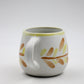 White mug with leaf patterns on a white background