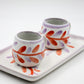 Two ceramic cups with floral patterns on a white tray
