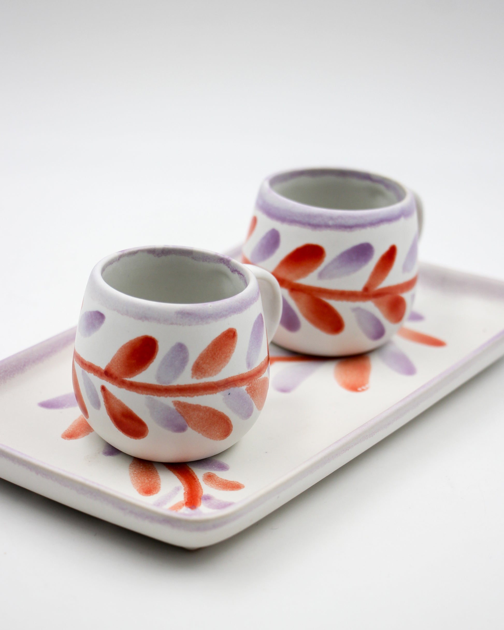Two ceramic cups with floral patterns on a white tray