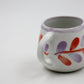 Ceramic mug with colorful abstract designs on a white background