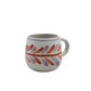 Ceramic mug with colorful leaf pattern on a white background