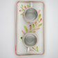 Two ceramic cups on a decorative tray with floral patterns on a light gray background