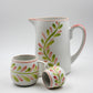 Ceramic pitcher and cups with floral patterns on a white background
