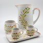 Ceramic pitcher and cups with floral design on a white background