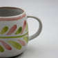 Ceramic mug with colorful leaf pattern on a white background