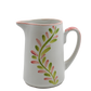White ceramic pitcher with pink and green leaf pattern on a white background