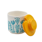 White container with blue floral pattern and yellow lid on a white background