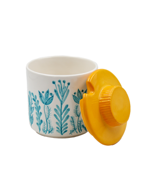 White container with blue floral pattern and yellow lid on a white background